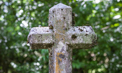 Ein steinernes Kreuz auf einem Friedhof. Ruhe und Andenken an die Verstorbenen.