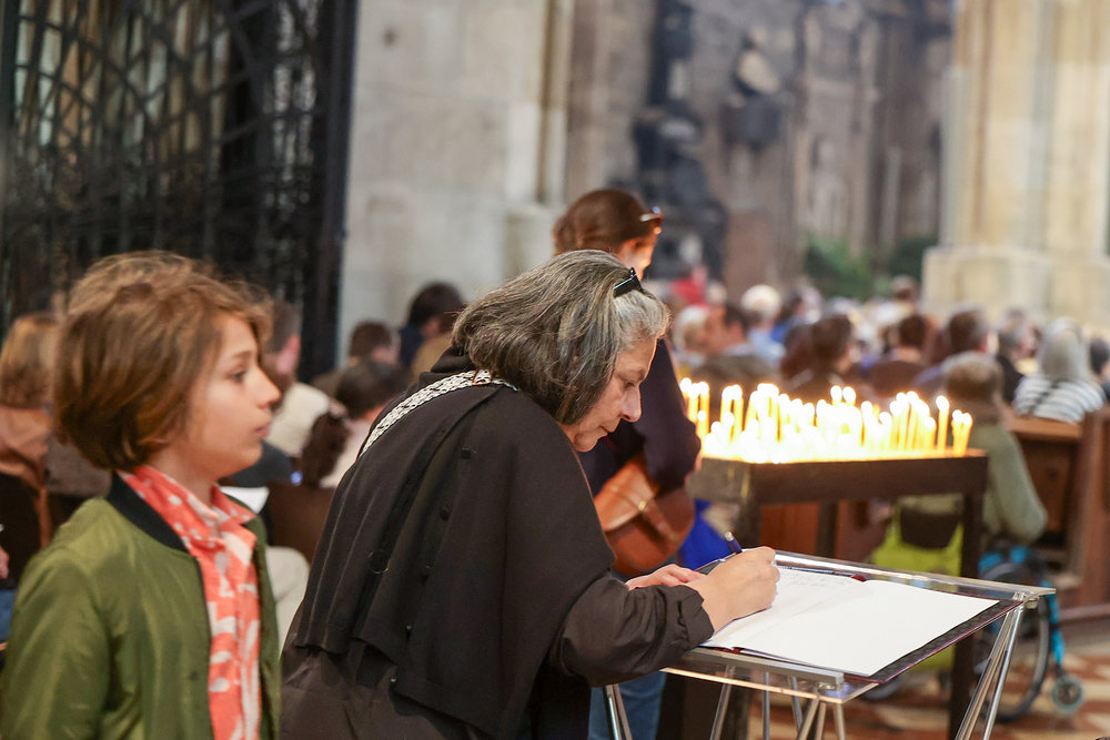 Frau trägt sich in Kondolenzbuch im Stephansdom zum Tod von Papst Franziskus ein / Erzdiözese Wien / Stephan Schönlaub Abschied von Papst Franziskus: Kondolenzbücher in ganz Österreich