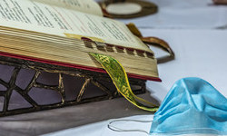 Ein Priester faltet die Hände und feiert den Gottesdienst am Altar, auf dem das Messbuch aufgeschlagen liegt, daneben eine einfache Atemschutzmaske, dahinter liturgische Geräte, am 8. Mai 2020 in Rom.