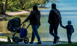 Eine junge Familie beim Spaziergang mit Kindern und Kinderwagen.