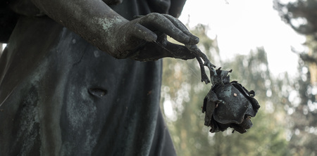 Ein Engel auf einem Friedhof hält eine Rose zum Abschied in den Hand