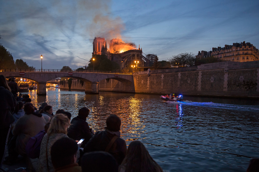 Notre-Dame brennt / Copyright 2019, KNA GmbH, www.kna.de, All Rights Reserved, Corinne Simon Menschen stehen am Ufer der Seine und blicken auf den Brand der Kathedrale Notre-Dame in Paris am 15. April 2019.