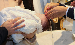 Newborn baby baptism, water with hands of priest.