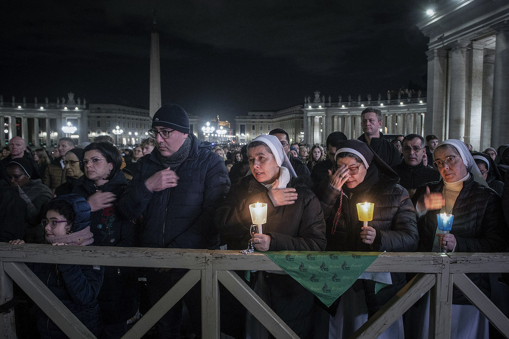 Menschen im Gebet / Copyright 2025, KNA GmbH, www.kna.de, All Rights Reserved, Alessia Giuliani Menschen hinter einer Absperrung darunter Ordensschwestern mit Kerzen, bei einer Rosenkranzandacht für den erkrankten Papst am 28. Februar 2025 auf dem Petersplatz im Vatikan.