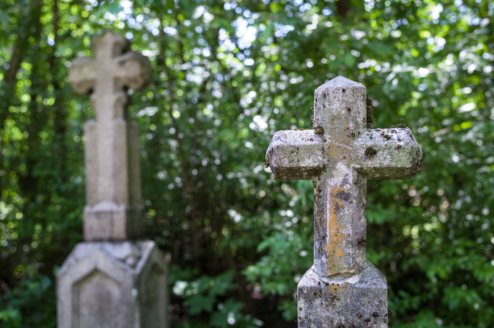 Ein steinernes Kreuz auf einem Friedhof. Ruhe und Andenken an die Verstorbenen.