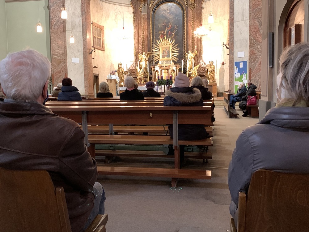 Gläubige in der Kirche mit Sicherheitsabstand und Maske