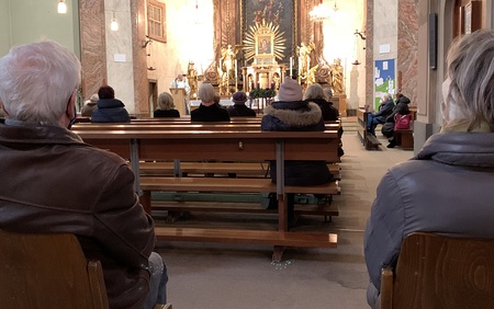 Gläubige in der Kirche mit Sicherheitsabstand und Maske