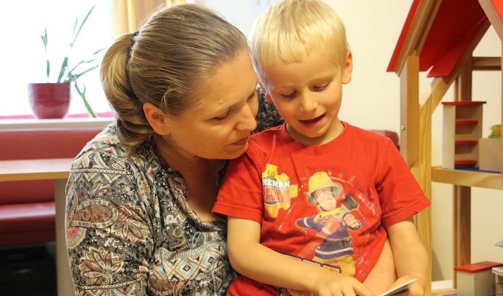 Mutter und Sohn lesen Buch / Caritas Socialis