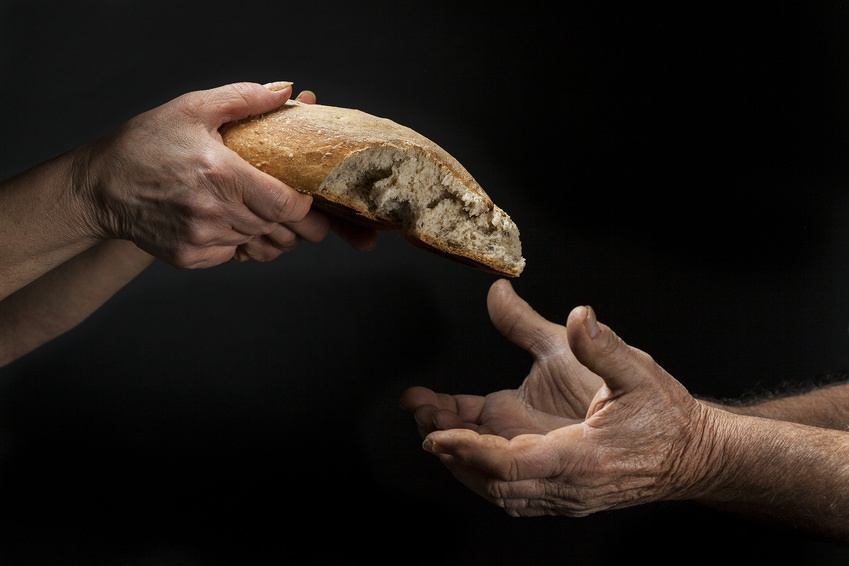 Mano di donna dona pagnotta di pane a un povero senzatetto. Concetto di povertà , emarginazione , fame nel mondo / ©nnerto - stock.adobe.com, nnerto - stock.adobe.com