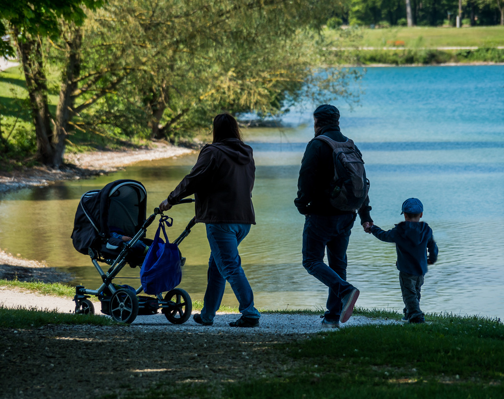 Eine junge Familie beim Spaziergang mit Kindern und Kinderwagen.